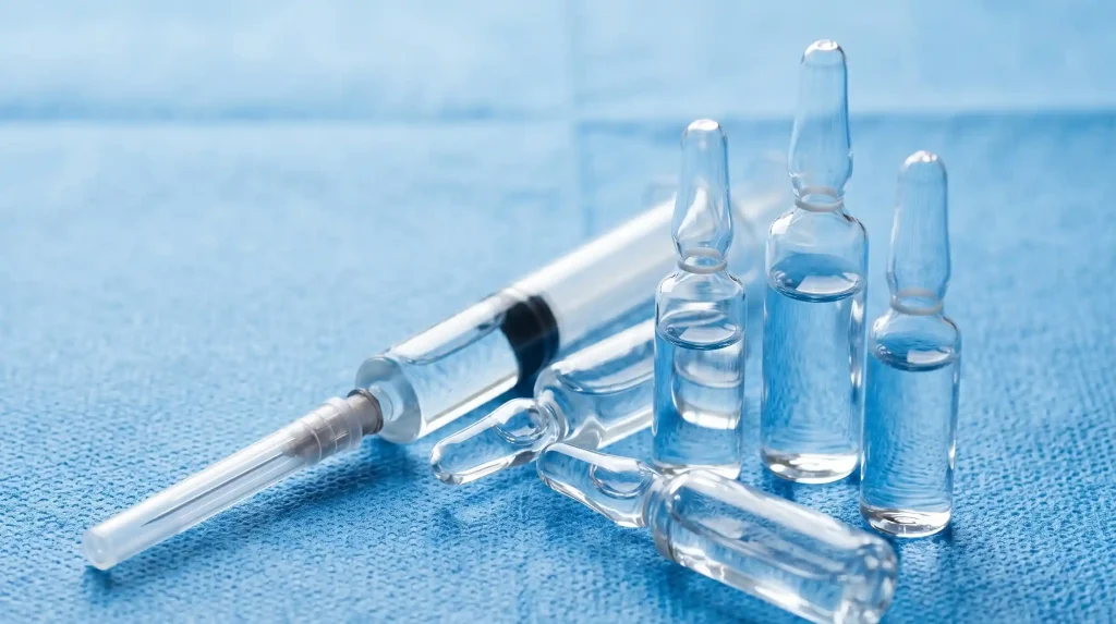 Glass medical ampoules and syringe on blue surgical drape representing atropine treatment protocol for mad honey poisoning